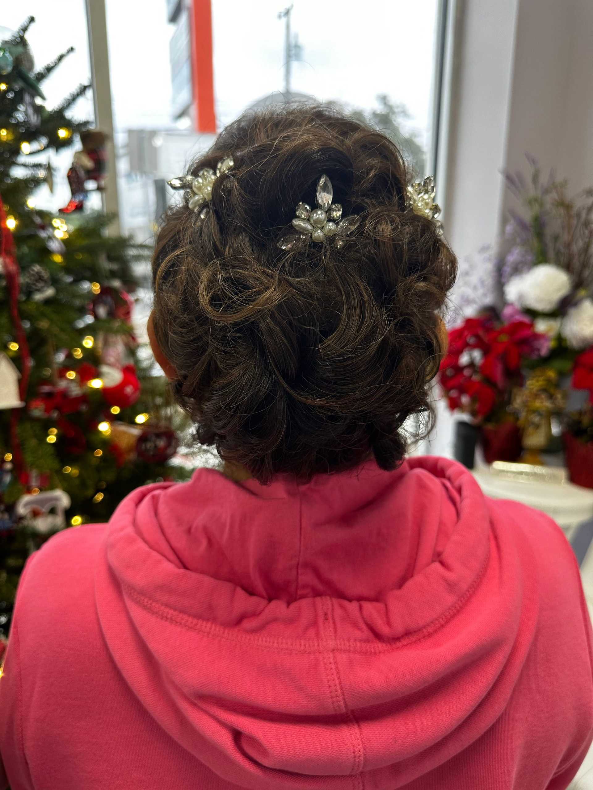 Elegant updo with jeweled hair accessory, set against a festive floral and Christmas decor backdrop.