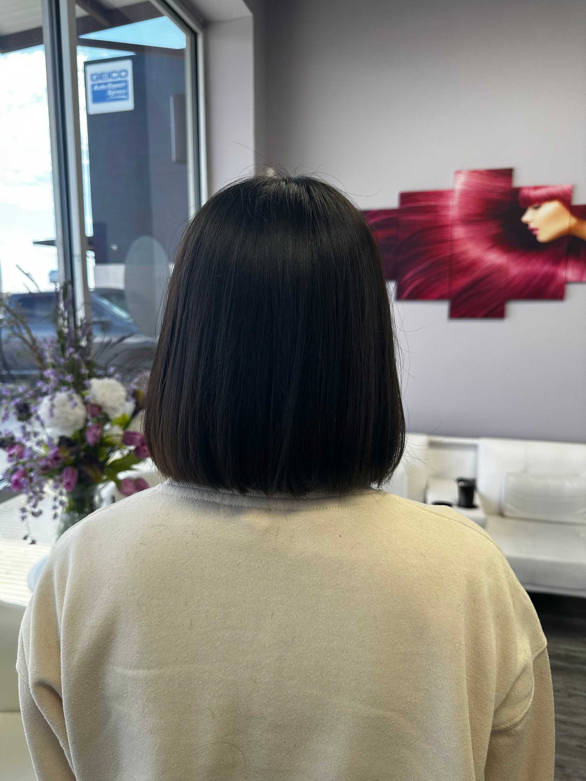 Short-haired person in a salon facing away, with floral decor and stylized artwork on the wall.